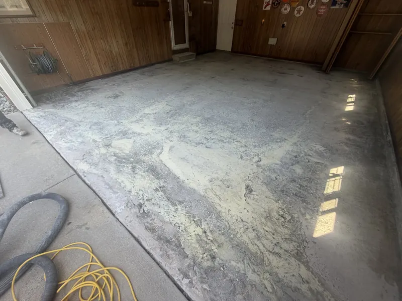 Garage slab before coating, ground and dusty with an air hose on the floor