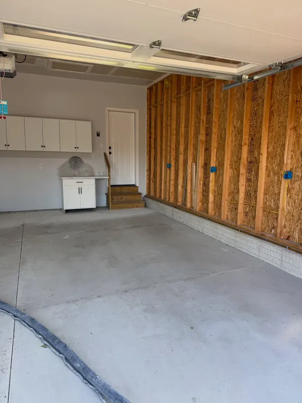 Before: Garage with unfinished stud walls and bare concrete before coating