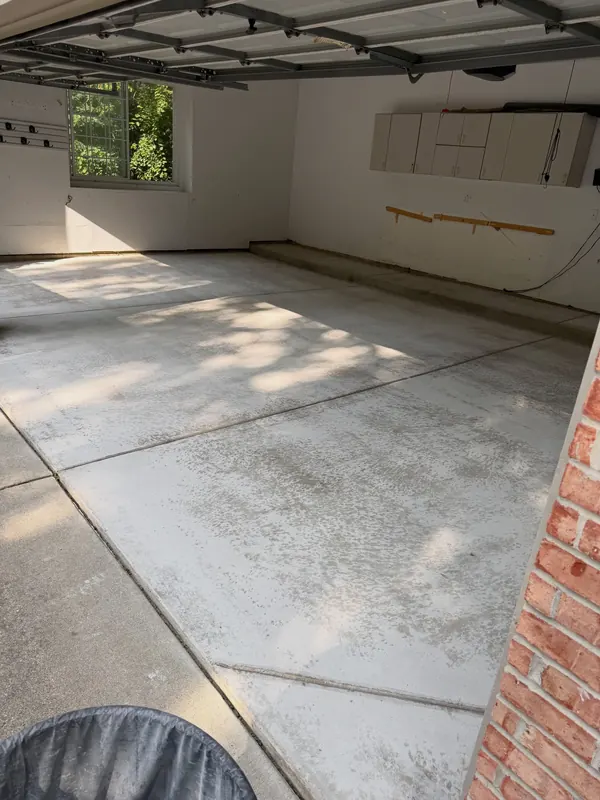 Worn garage floor with stained, uneven concrete before our grind and recoat