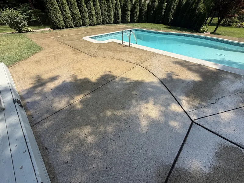 Pool deck coated in a light flake finish beside an in-ground pool