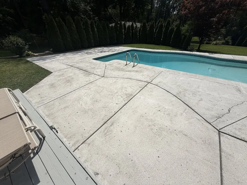 Pool deck before coating with weathered, stained concrete and visible cracks