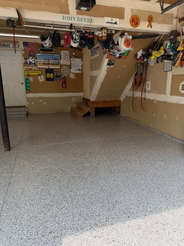 Garage with a flake floor below a pegboard wall of tools and helmets