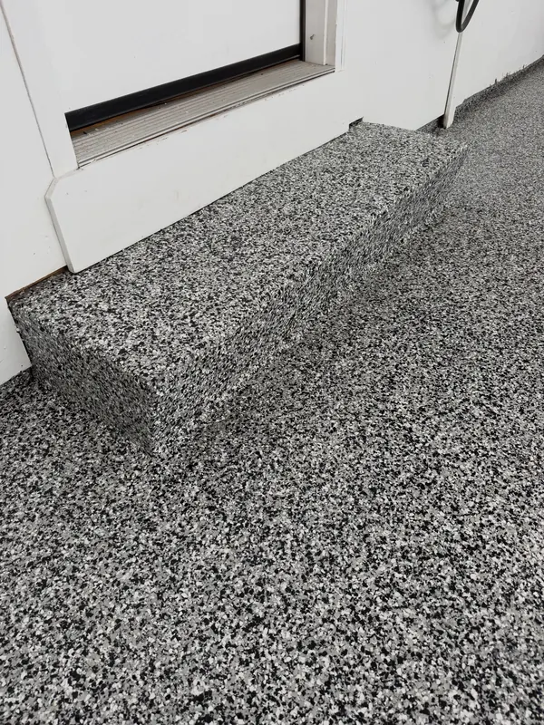 Concrete step into the house coated in black, white and gray flake