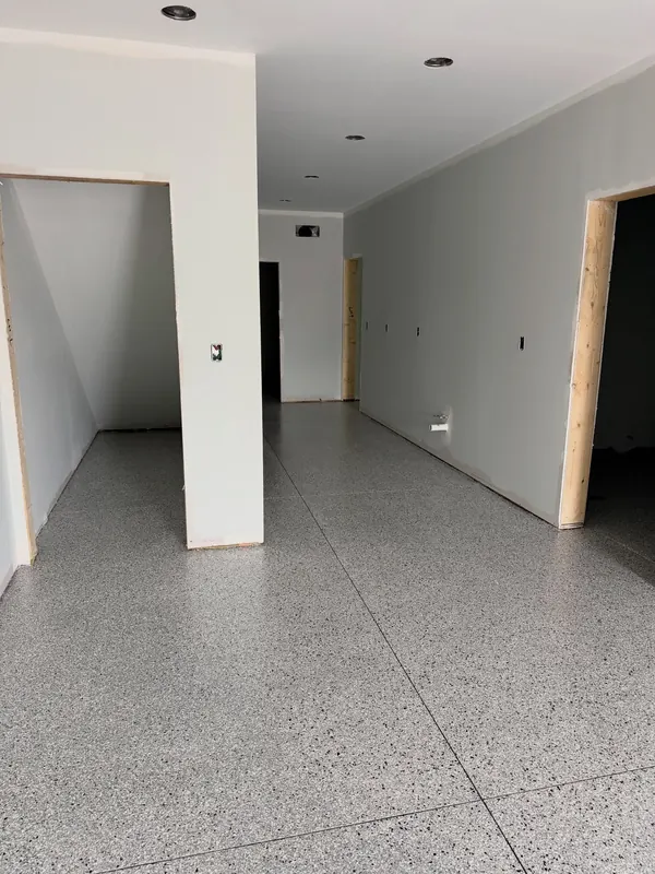 New-construction hallway with fresh white walls and a light flake floor coating