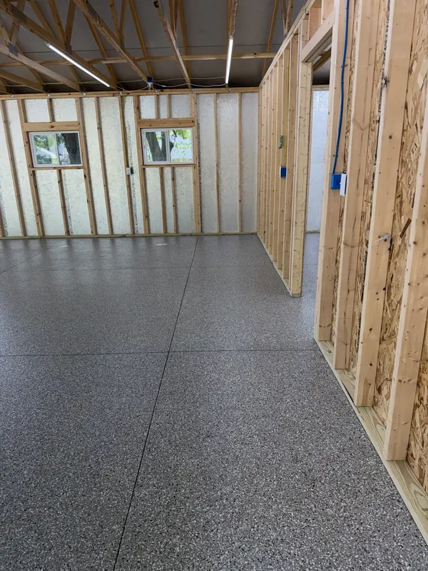Pole building room with framed stud walls and a freshly coated flake floor