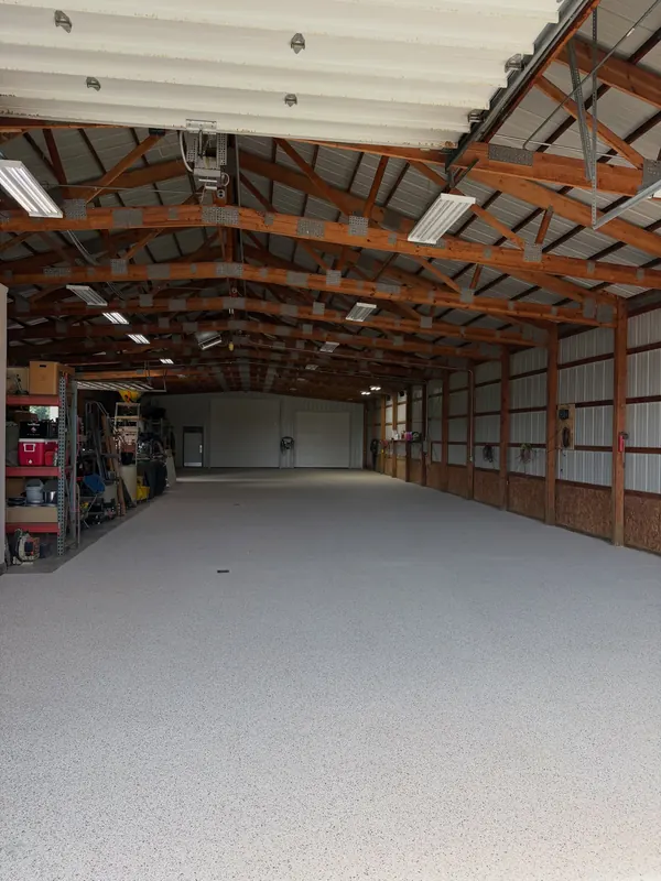 Long pole building shop with a light flake floor coating under wood trusses