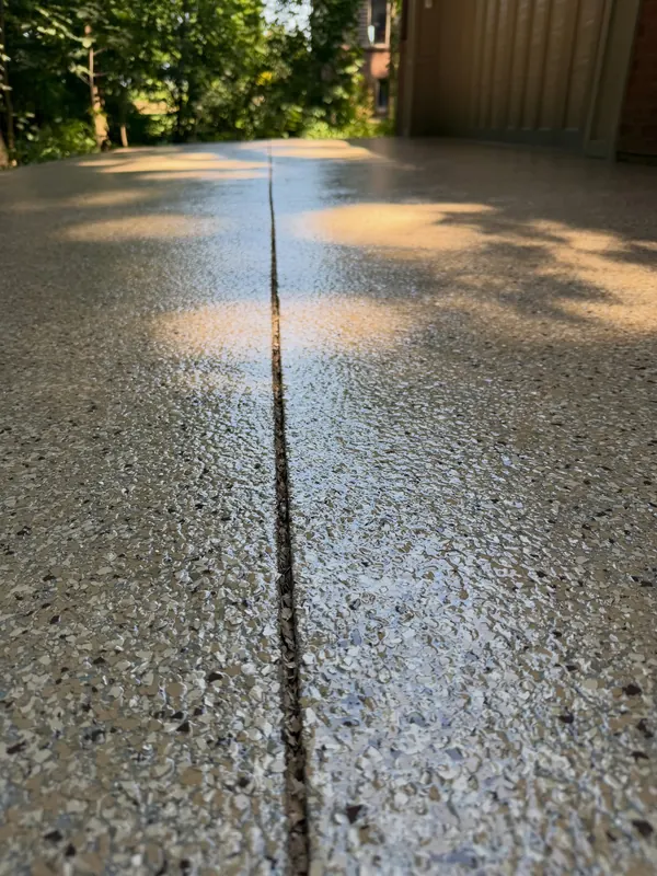 Close-up of a coated garage floor with a clean saw-cut expansion joint running through the flake