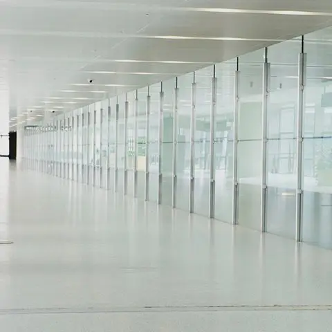 A long hallway with glass walls and white floors.